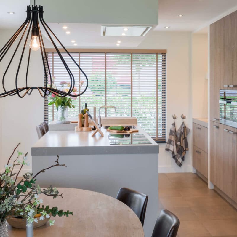 Impressie van een ruime keuken met eiland en kastenwand met inbouw apparatuur.