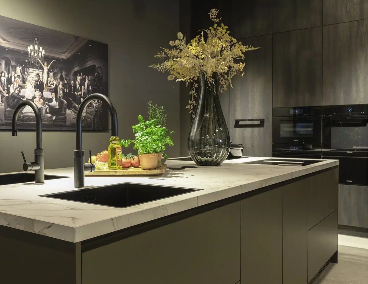 Impressie van een keuken met groene wanden, kasten en kookeiland.