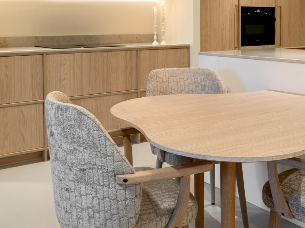 aan het kookeiland bevestigde houten eettafel met organische rondingen