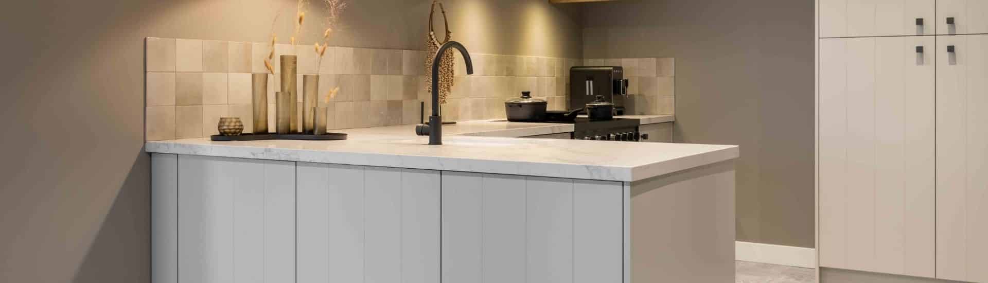 Sfeerbeeld van een keuken met greige kookeiland en kastenwand.