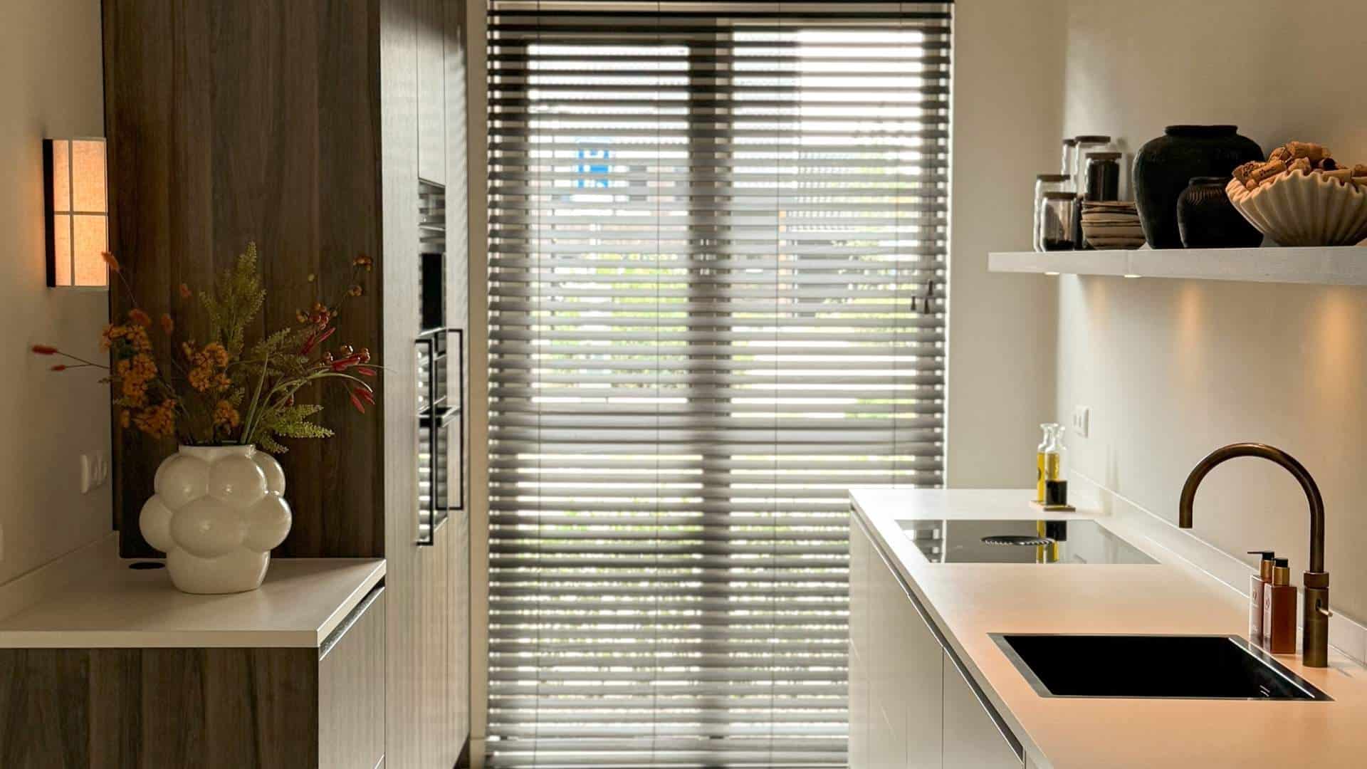 Impressie van een keuken met een rechte opstelling. Het is een keuken zonder bovenkastjes, maar met een kastenwand en plank om spullen op te bergen.