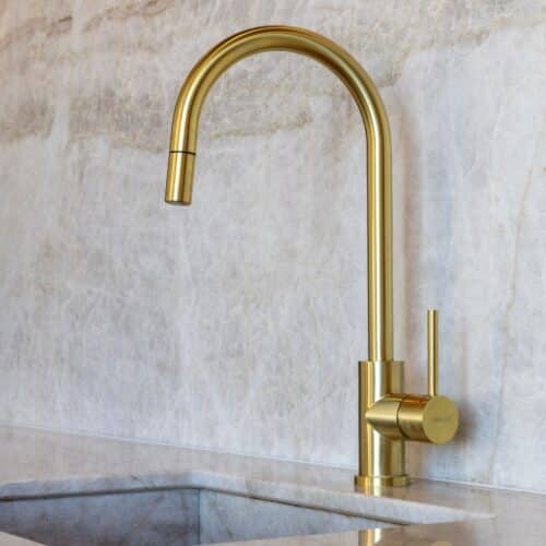 Close-up van een gouden Quooker, geplaatst op een glanzend marmer blad.