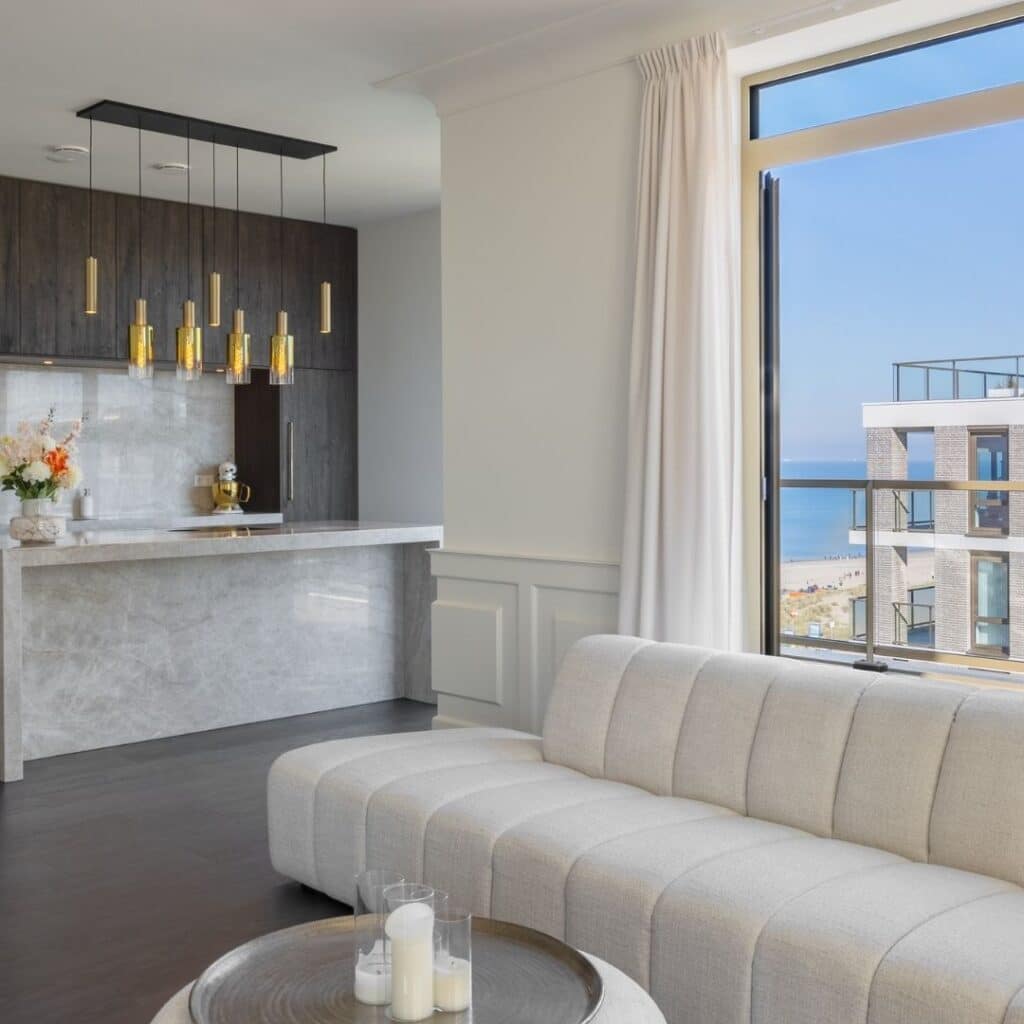 Impressie van een appartement met luxe keuken, voorzien van glanzend marmer met gouden aders, een kookeiland en donker hout.