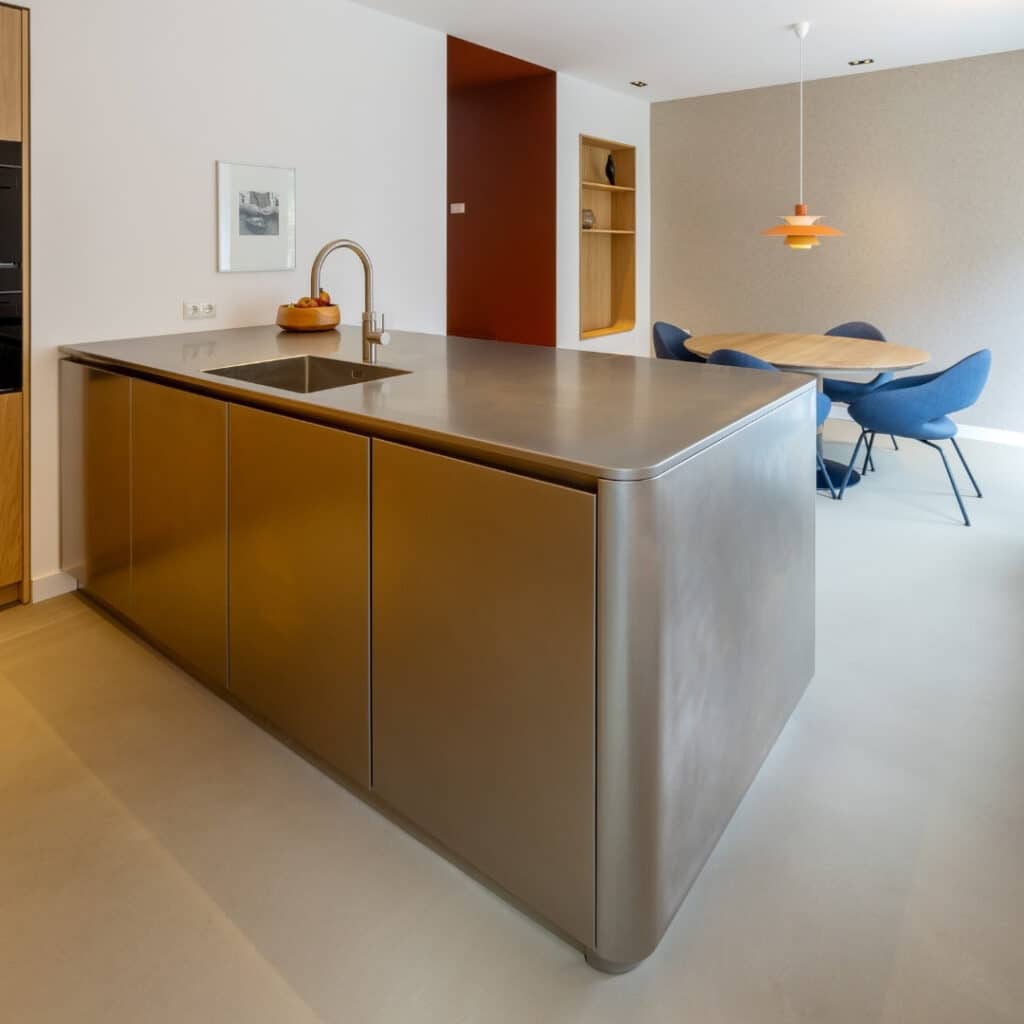 Impressie van een RVS schiereiland, voorzien van lades, kasten en een design wasbak met Quooker.