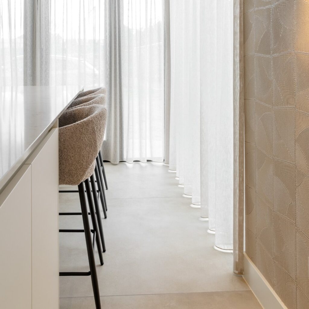 Impressie van een Japandi stijl keuken met kookeiland, voorzien van bar met drie barkrukken.