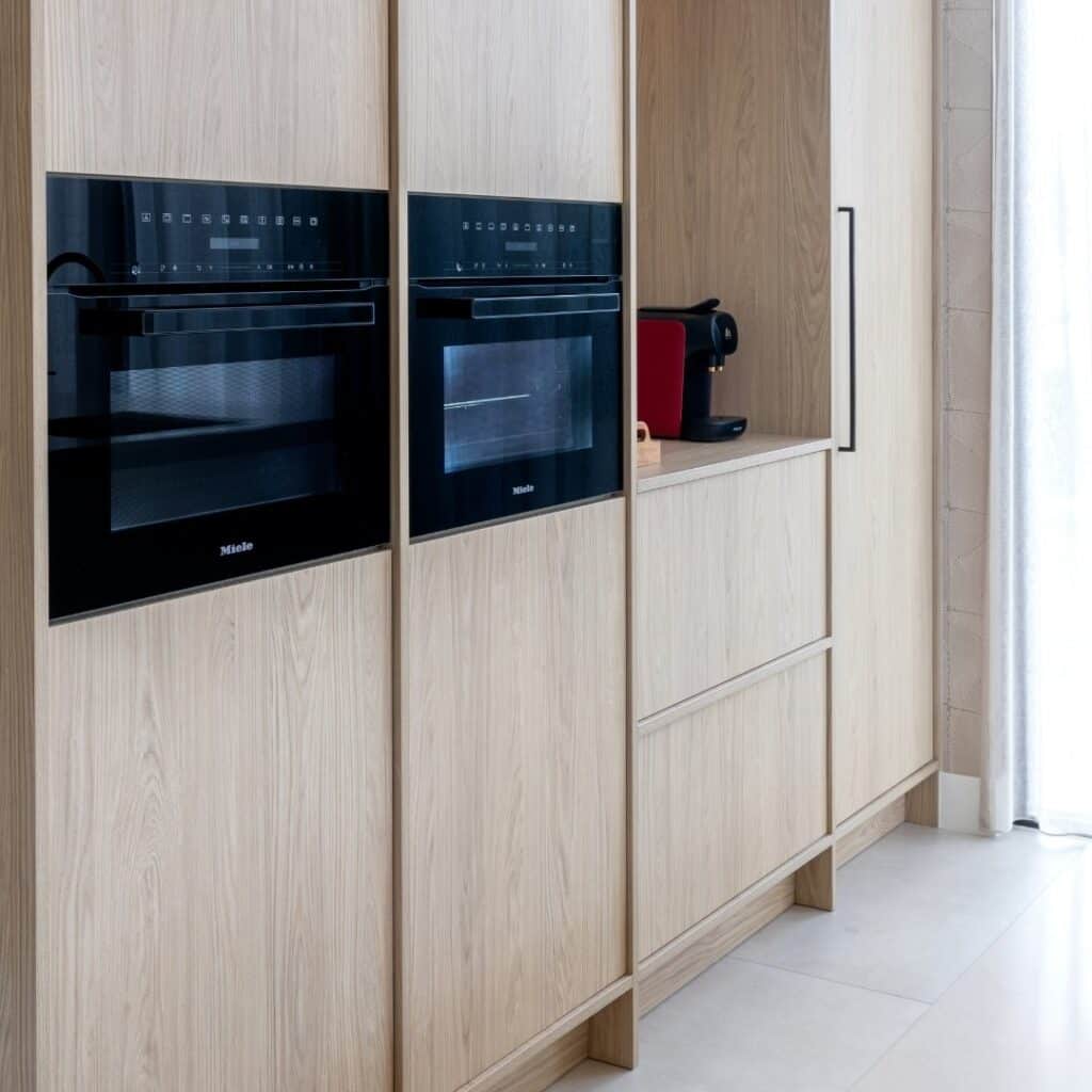 Impressie van een Japandi stijl keuken met licht eiken kastenwand, voorzien van Miele ovens.