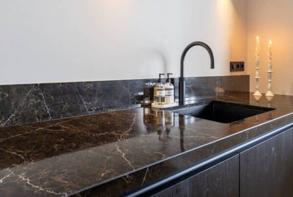 Impressie van een moderne hoekkeuken met een werkblad in zwart marmerlook.