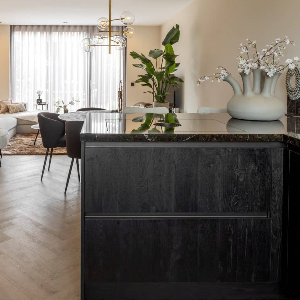 Impressie van een moderne hoekkeuken met zwarte lades en een zwart marmerlook werkblad.