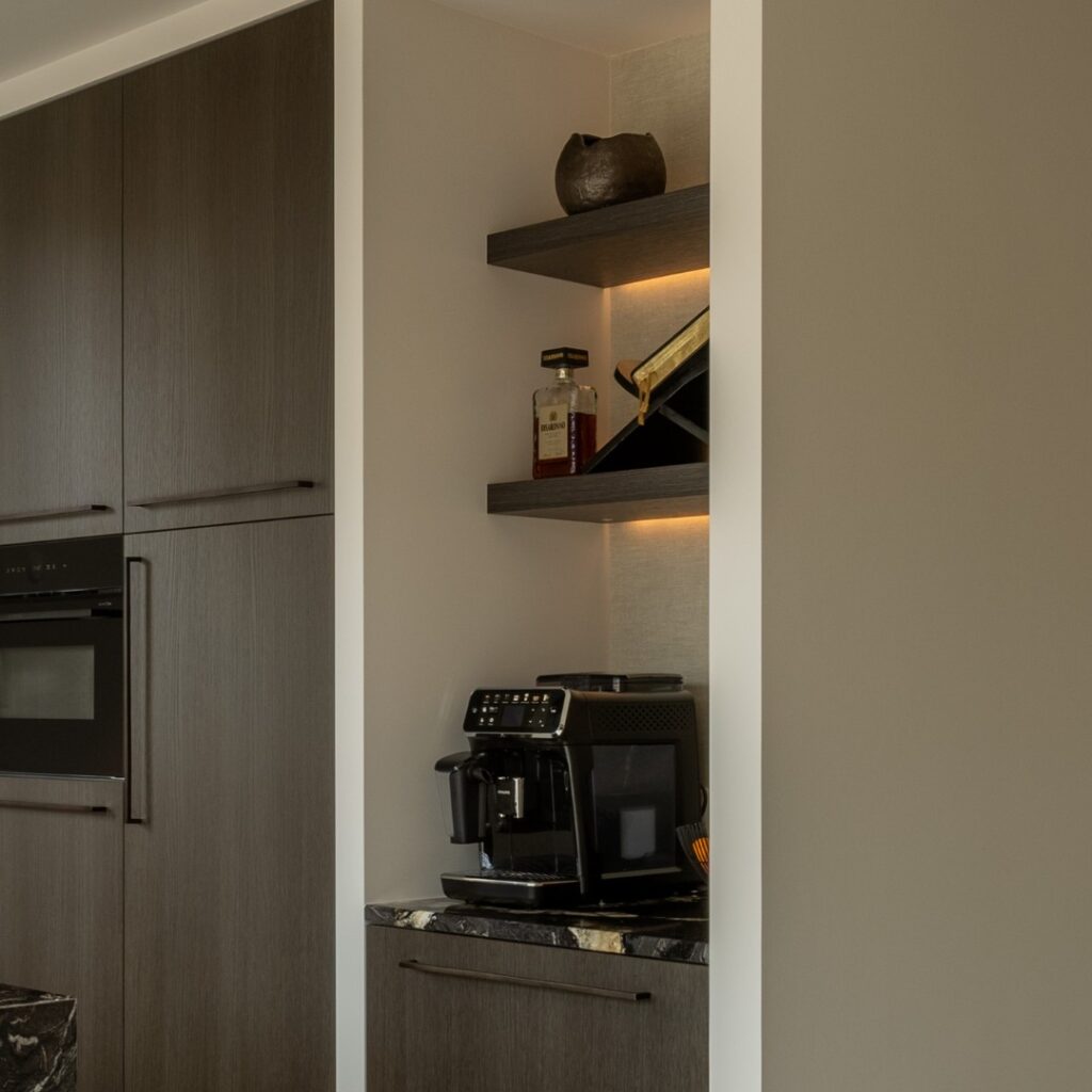 Impressie van een houten kastenwand, met daarnaast een nis met een koffiecorner.