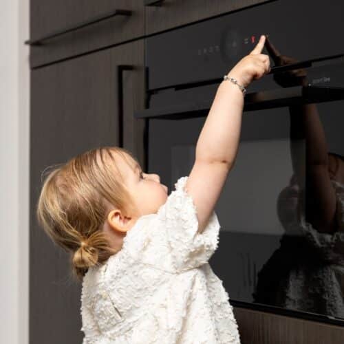 Impressie van een kind die een inbouwoven bedient.