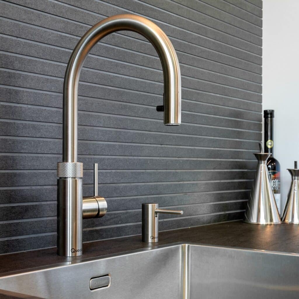 Impressie van een nis met een design wasbak en Quooker. De nis heeft een achterwand van antraciet tegels.