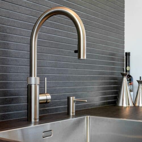 Impressie van een nis met een design wasbak en Quooker. De nis heeft een achterwand van antraciet tegels.