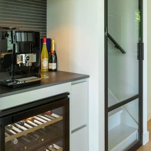 Impressie van een moderne woning, met de focus op een nis met een koffiemachine en een wijnklimaatkast.