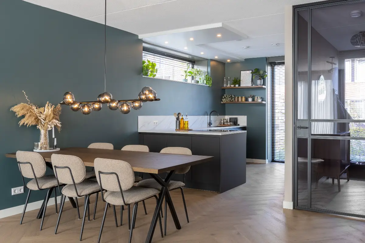 Stijlvolle eethoek met een diepgroene wand, houten eettafel met bouclé stoelen en een moderne designlamp met glazen bollen.