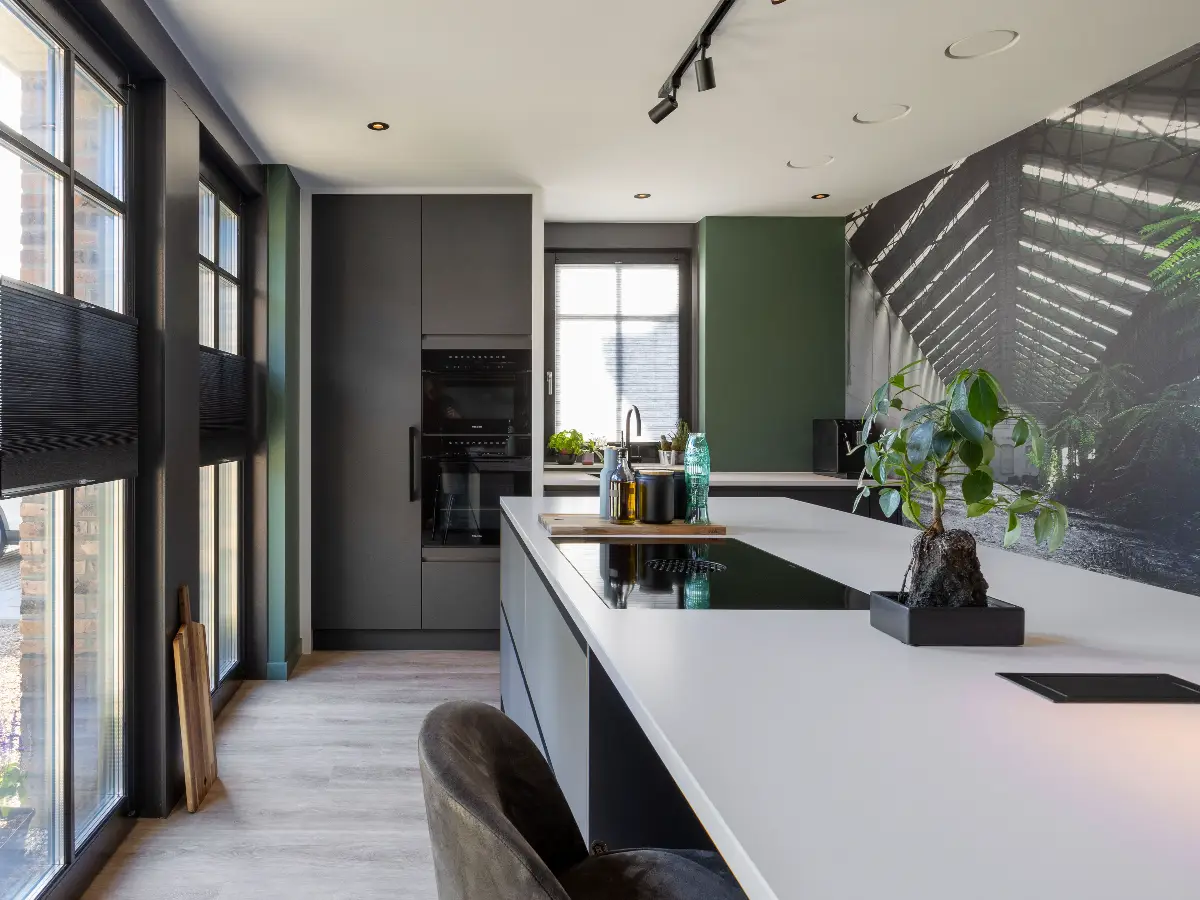 Moderne keuken met wit kookeiland, groene wand en industriële fotowand.